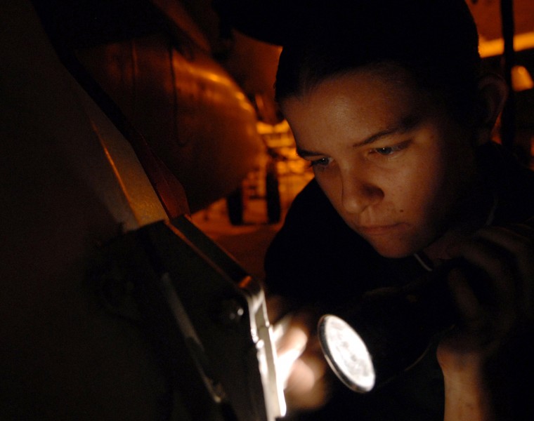 US Navy 061115-N-7526R-025 As red lights encircle the hangar bay of the Nimitz-class aircraft carrier USS Ronald Reagan (CVN 76), Aviation Boatswain's Mate (Equipment) 3rd Class Kristina Stewart uses a flashlight to help her pa
