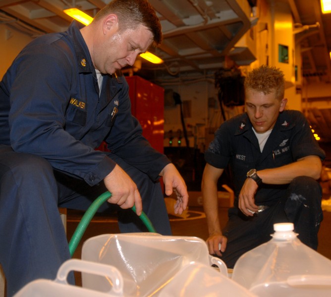 US Navy 080912-N-7544A-024 Chief Gunner's Mate William Walker and Aviation Ordnanceman 3rd Class Chris West, both embarked aboard the amphibious assault ship USS Kearsarge (LHD3) fill two-and-a-half gallon water containers