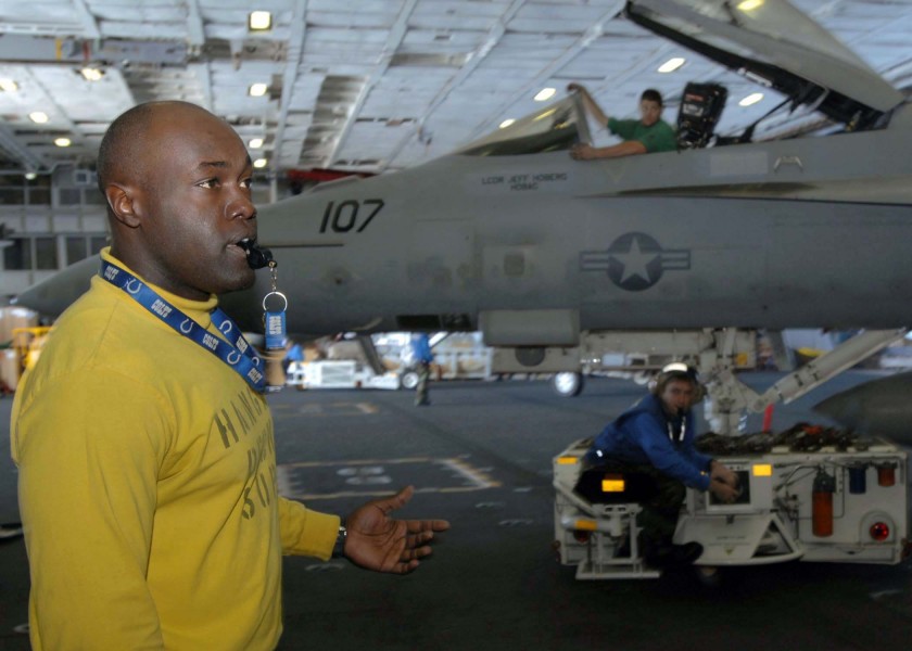 US Navy 081119-N-8822R-019 Aviation Boatswain's Mate (Handling) 2nd Class Tyre Reese directs hangar deck personnel as a tractor driver re-positions an F-A-18 Super Hornet