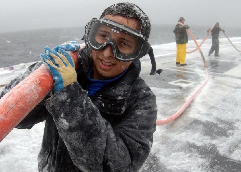 US Navy 100114-N-6688C-281 Aviation Boatswain's Mate (Handling) Airman Jonathan Rivera carries a hose during a counter measure wash down on the flight deck of the 