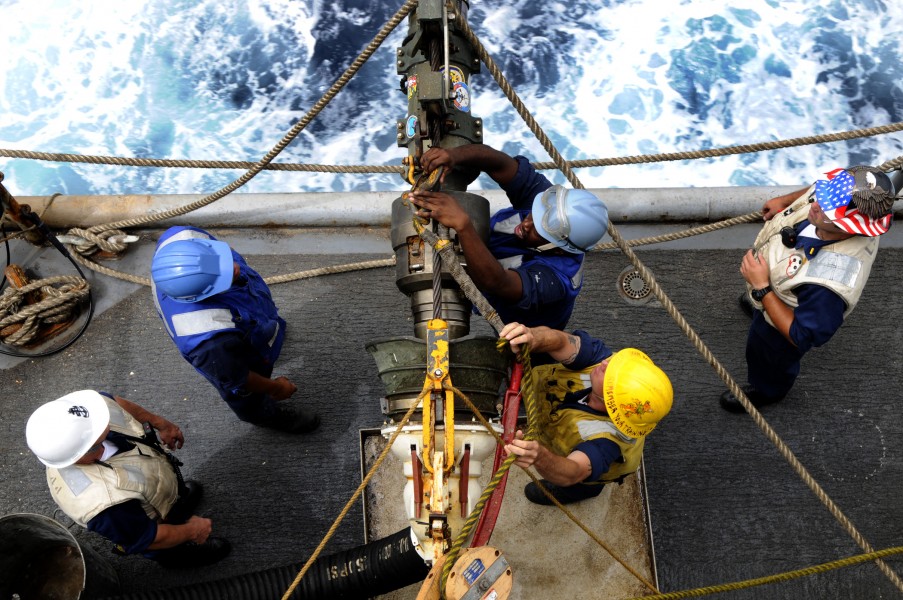 US Navy 100324-N-7948C-252 Aviation Ordnanceman Airman Raymond Thomas detaches the span line as Boatswain's Mate 2nd Class Bradley Gnage assists during an underway replenishment