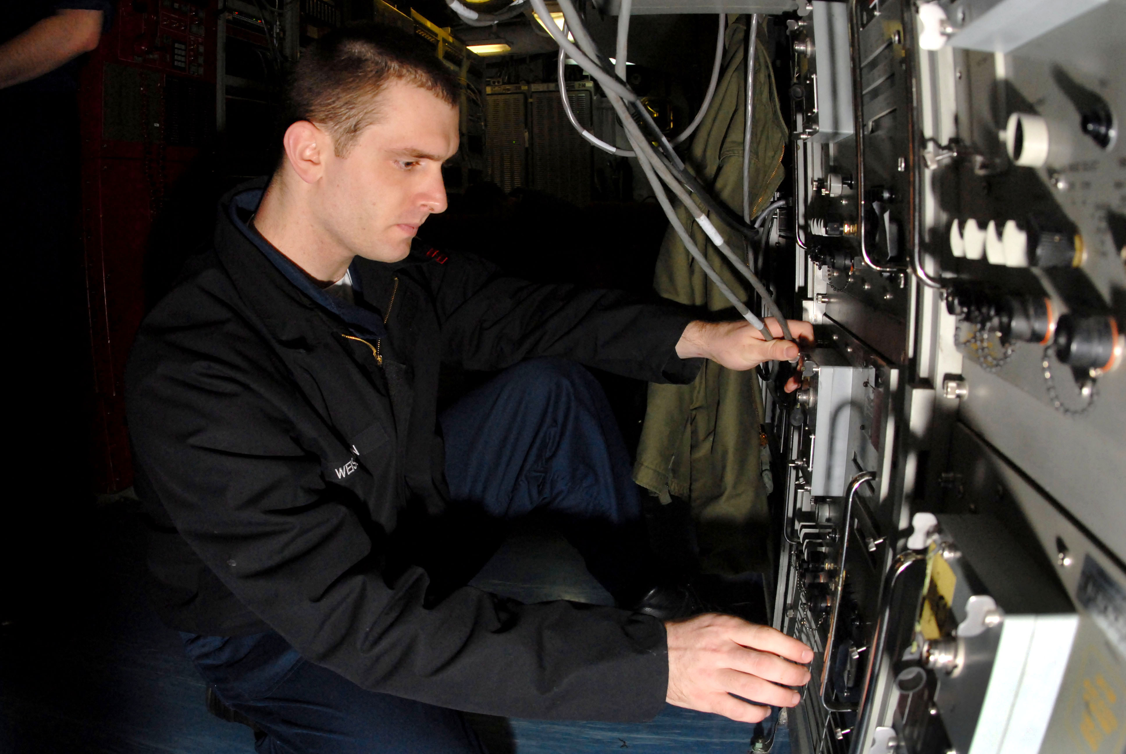 US Navy 070306-N-3038W-086 Information Systems Technician 2nd Class Dan Wiessman, assigned to combat systems department, checks satellite communications for voice networks aboard Nimitz-class aircraft carrier USS John C. Stenni