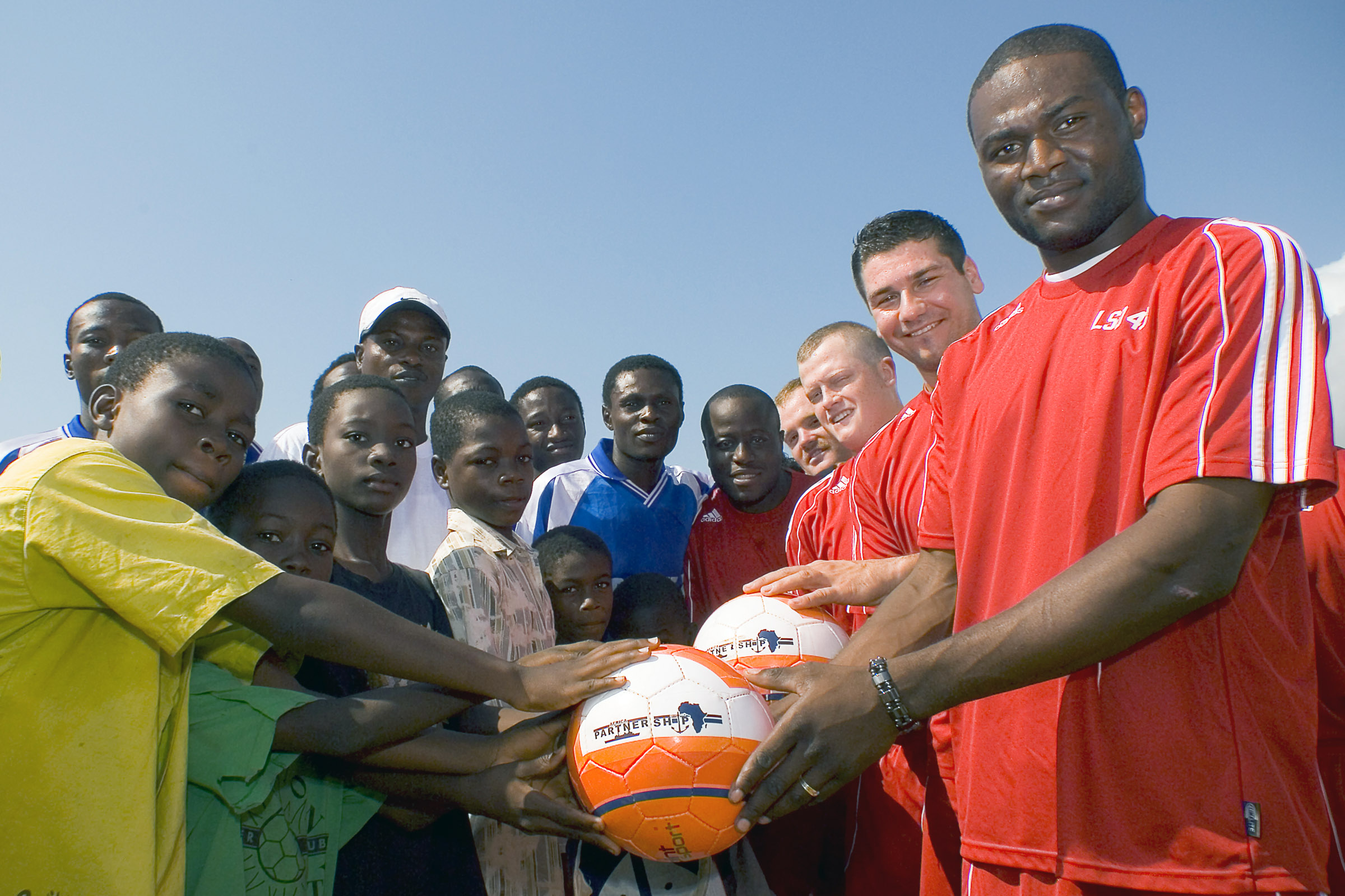 US Navy 071123-N-8483H-002 Sailors assigned to the amphibious dock landing ship USS Fort McHenry (LSD 43) present soccer balls to children in support of Africa Partnership Station (APS)