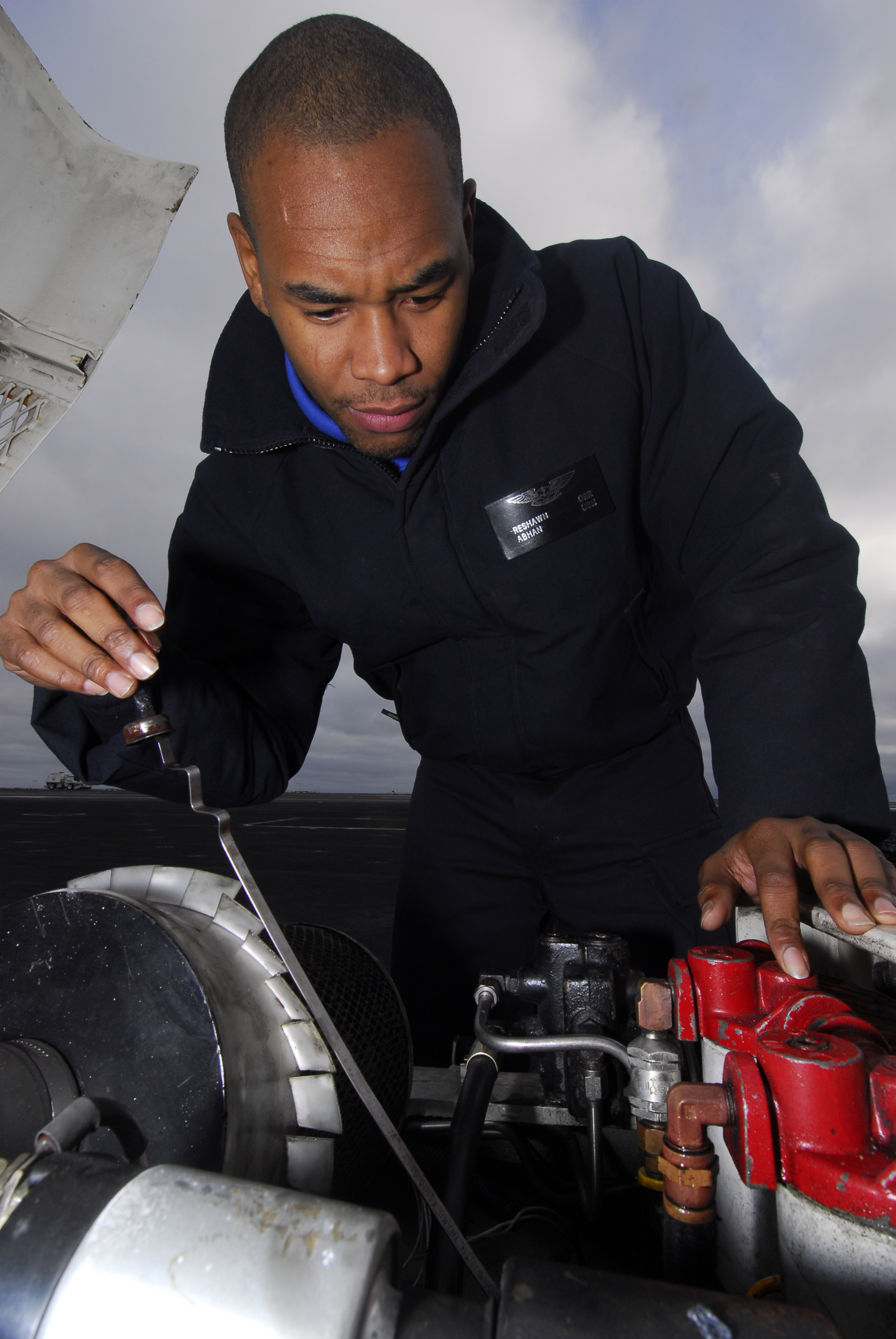 US Navy 091204-N-2475A-013 Aviation Boatswain's Mate (Handling) Airman Reshawn Orr, from Orlando, checks the oil of aircraft towing tractor on the flight deck aboard the Nimitz-class aircraft carrier USS John C. Stennis (CVN 74