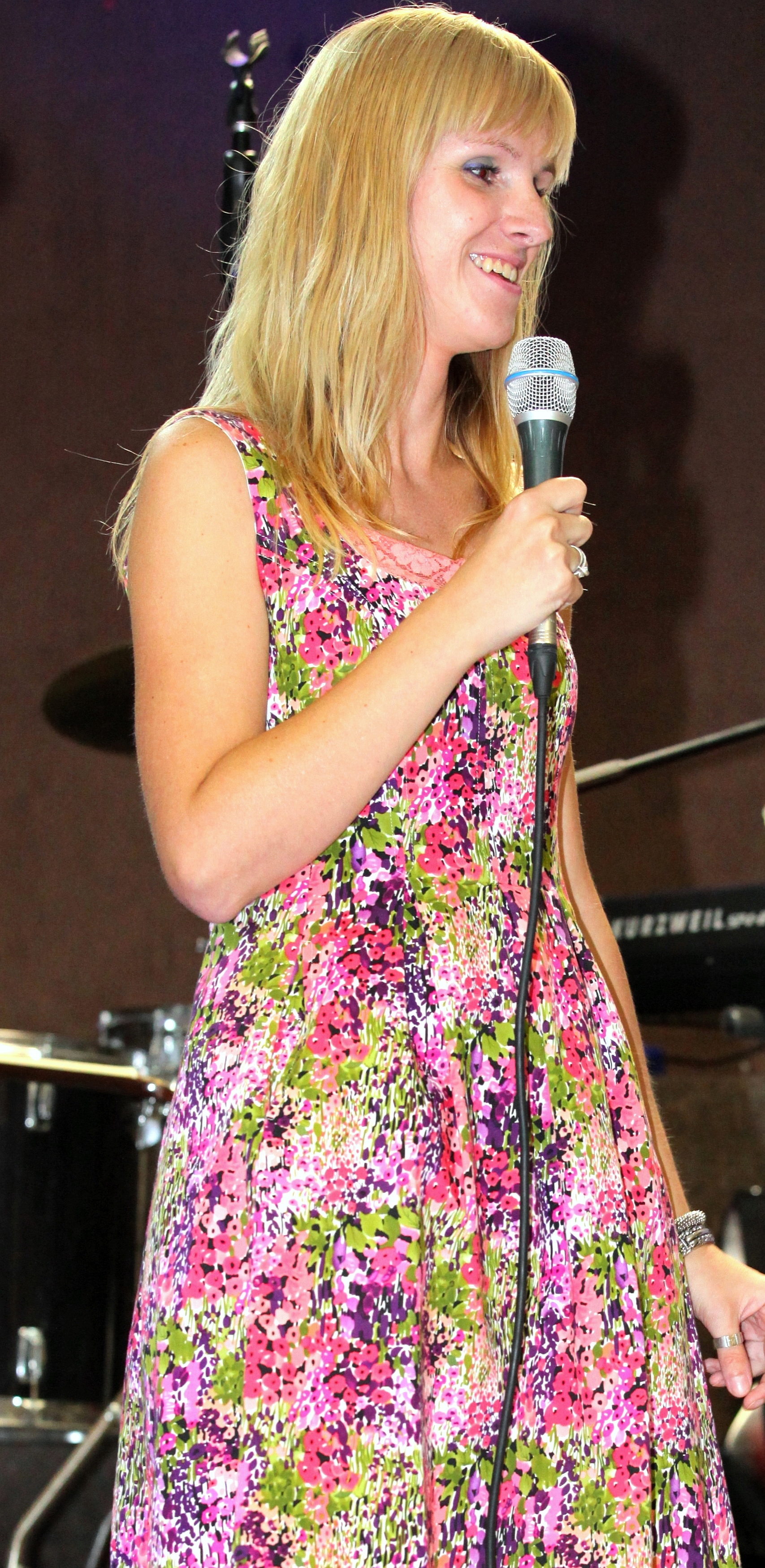 a blond girl in a colorful dress holding a microphone at a protestant gathering in July 2013, image 4/7
