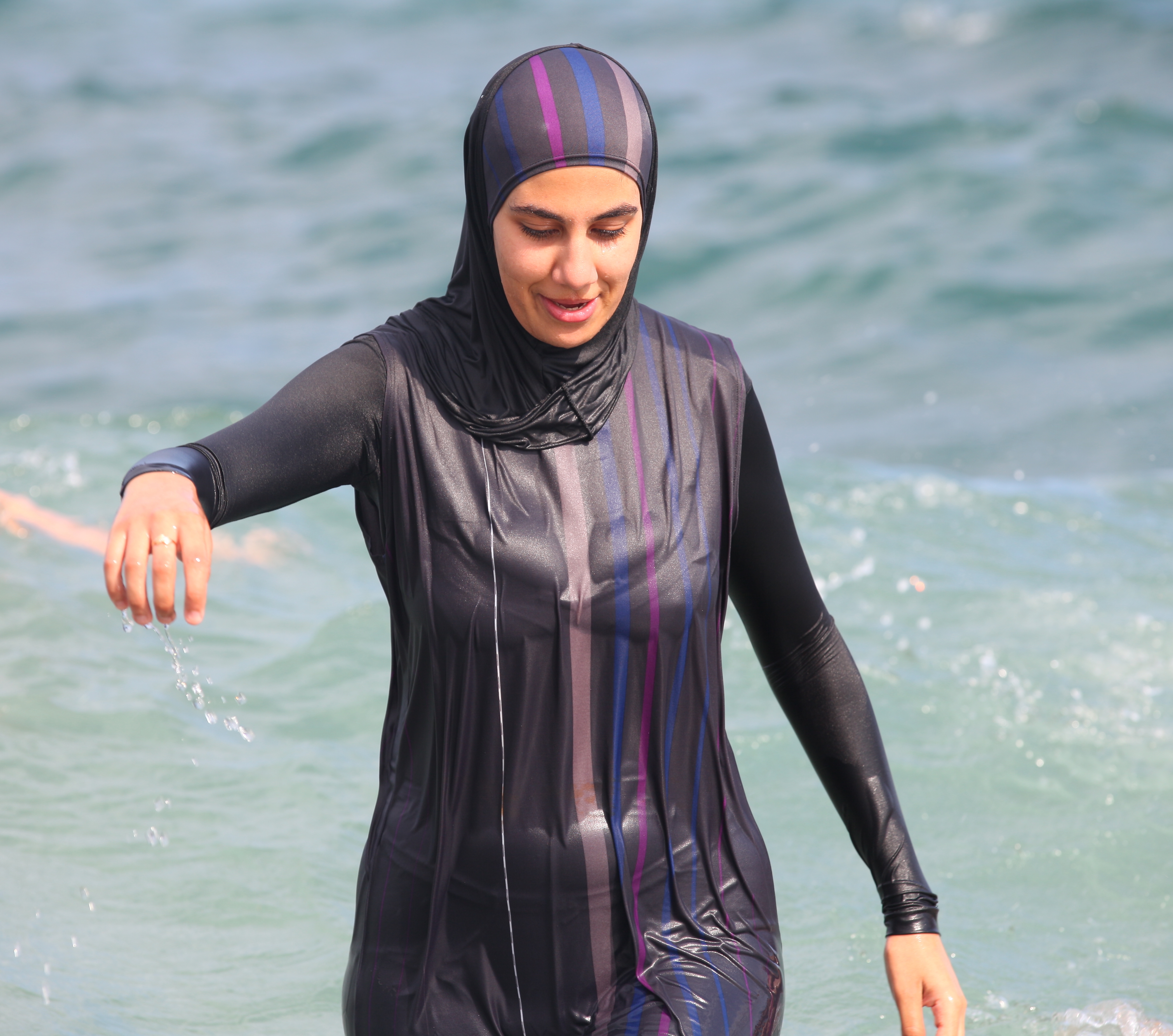 a fully-clothed woman bathing in the Mediterranean Sea in August 2013, photo 2/2