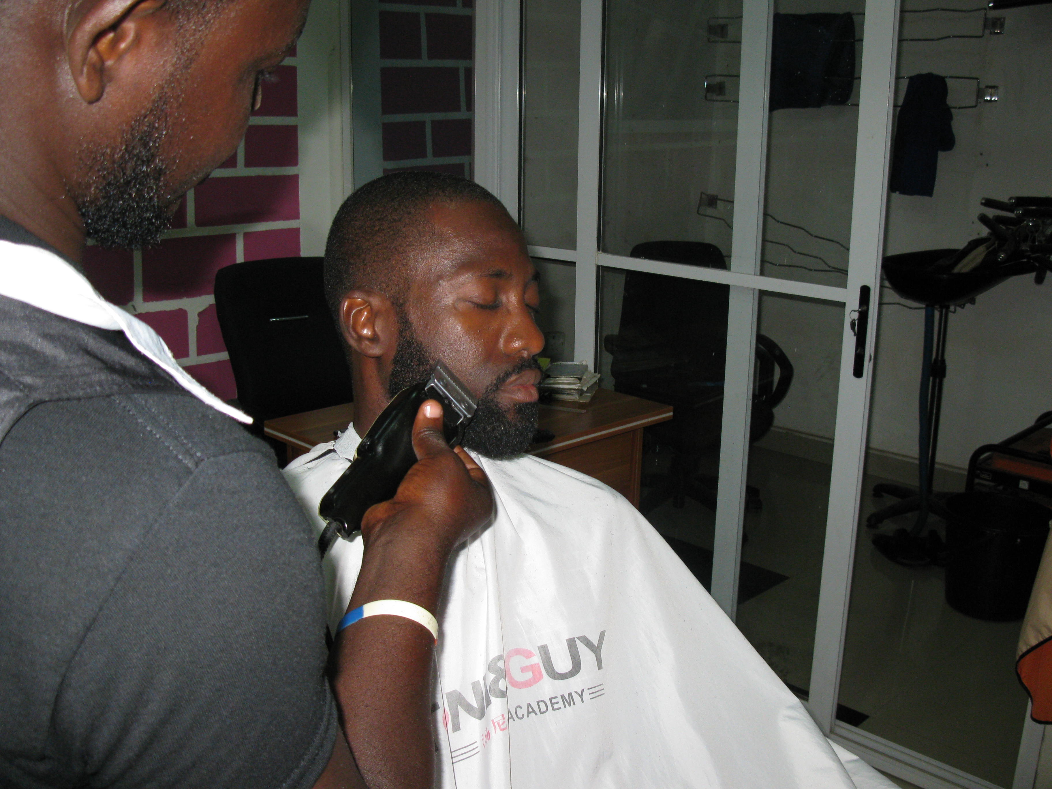 A Ghanaian Barber trimming a beard