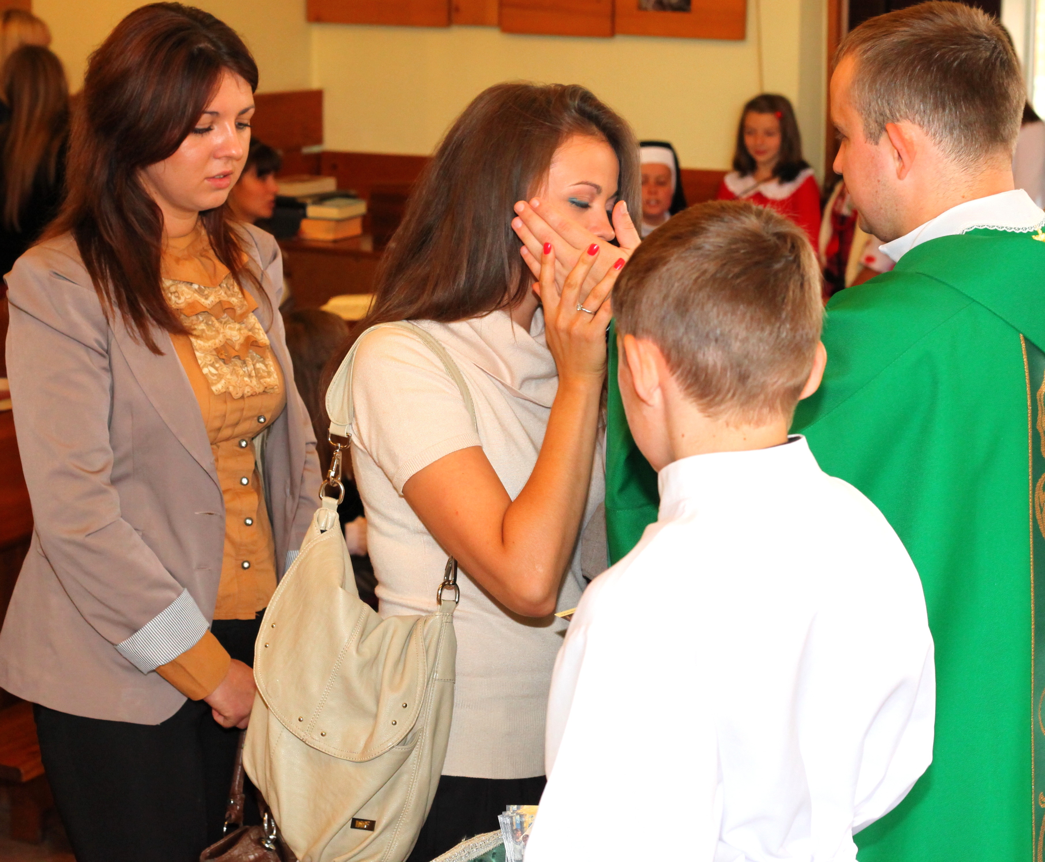 a beautiful charming young Catholic woman kisses the hand of a young padre