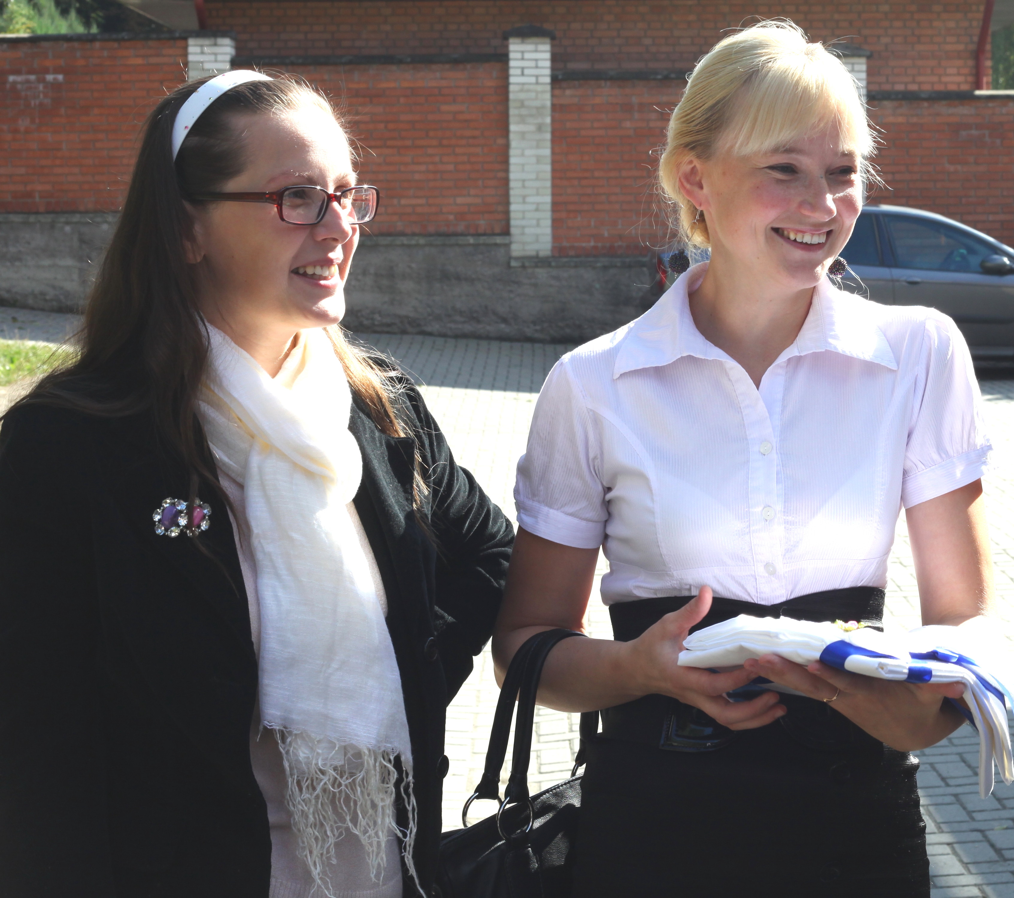 two young pretty smiling Catholic women at a baby baptism sacrament