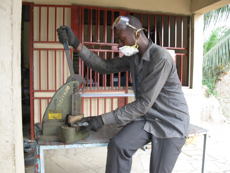 A Ghanaian Metal Fabricator cuts a metal plate