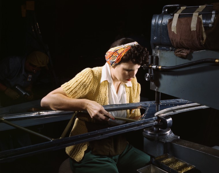 A girl riveting machine operator at the Douglas Aircraft Company plant joins sections of wing ribs