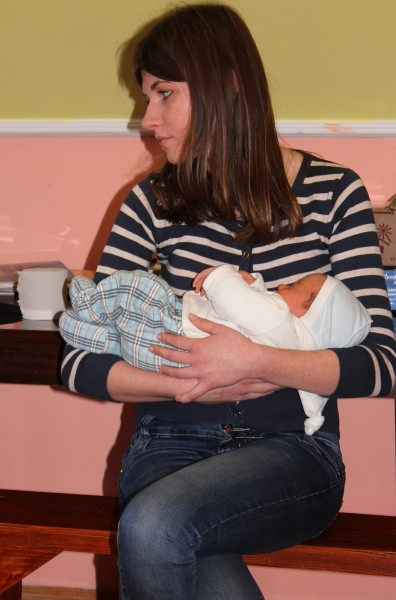 a pretty brunette girl in a Catholic kindergarten holding a baby
