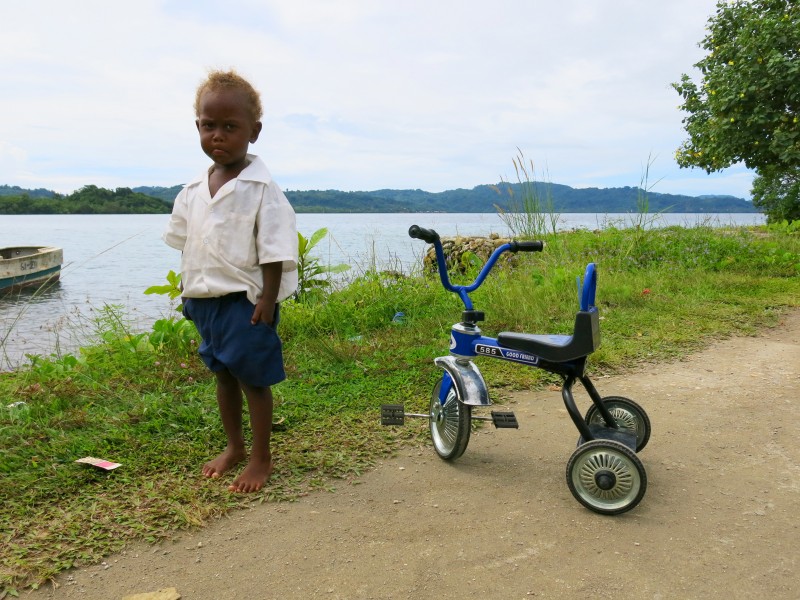 A small boy in a school uniform stands next to his tricycle. (10663272896)