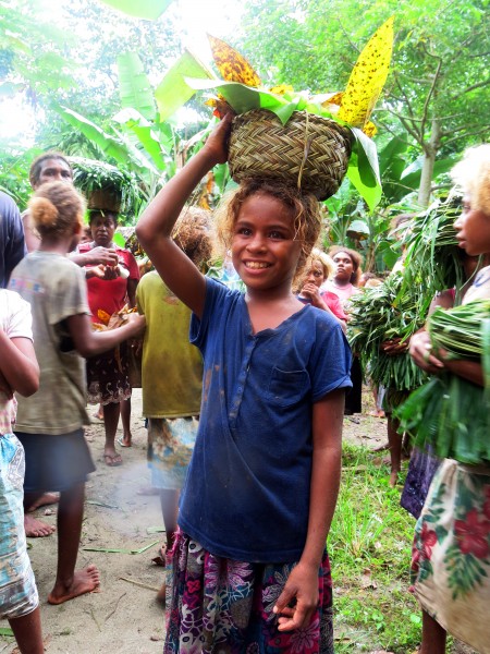 A young girl (around 13 years old) carries a basket on her head filled with food. (10664493196)