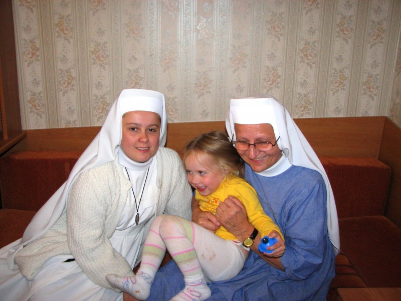Two Catholic nuns playing with a small blond child girl, picture 3