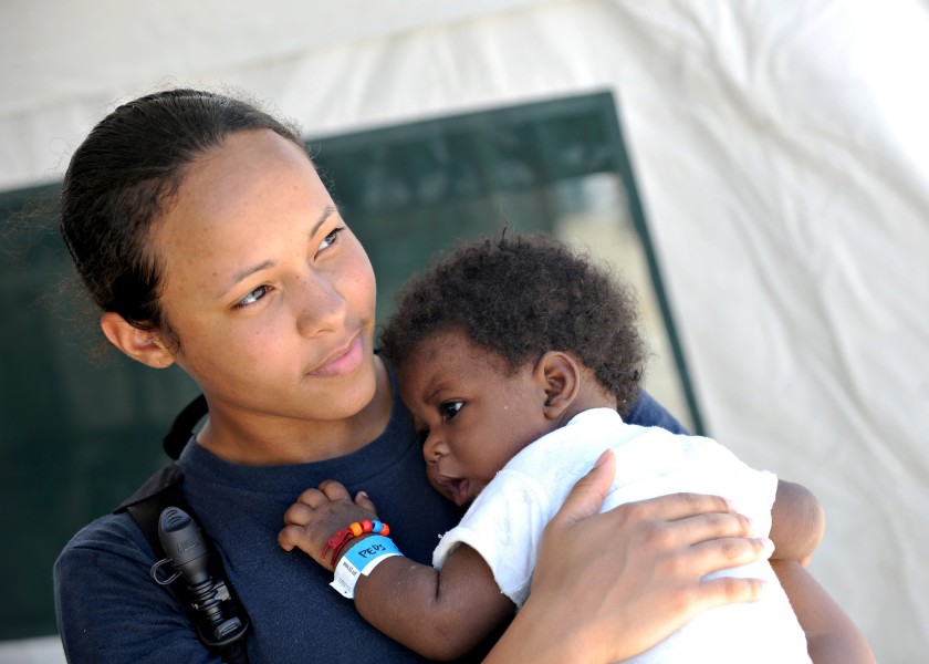 Defense.gov News Photo 110819-N-NY820-351 - U.S. Navy Hospitalman Cherie Williams holds a patient at the Terminal Varroux medical site in Port-au-Prince Haiti on Aug. 19 2011 during