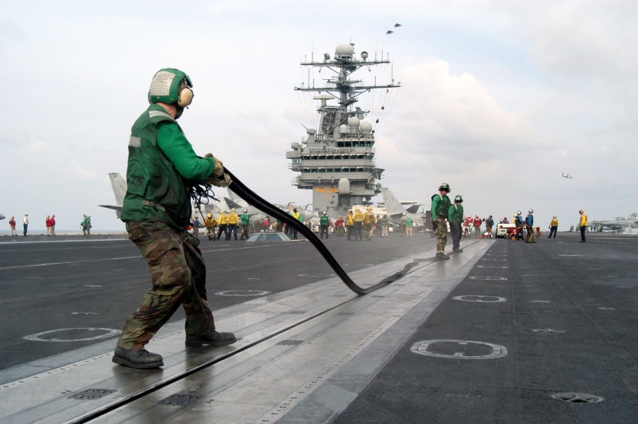 US Navy 030317-N-7265D-503 Aviation Boatswain's Mates place a rubber gasket in catapult ^2 aboard USS Theodore Roosevelt (CVN 71) after flight operations to keep debris from falling insides