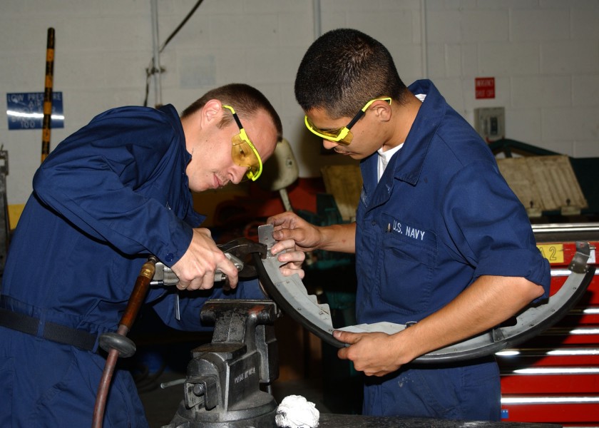 US Navy 030618-N-3970R-001 Aviation Structural Mechanic 2nd Class Jason Lively and Aviation Mechanic Airman Rafael Bustamente work together to rivet an air baffle