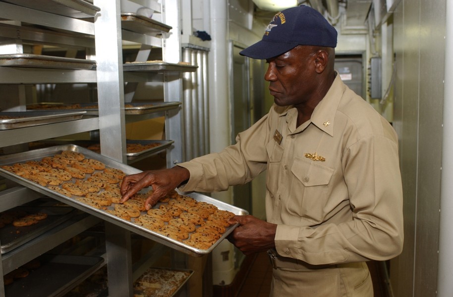 US Navy 031023-N-8295E-036 Chief Warrant Officer (CWO5) Leon A. Cole from Antigua, West Indies, checks recently baked cookies during one of his daily walk through inspections
