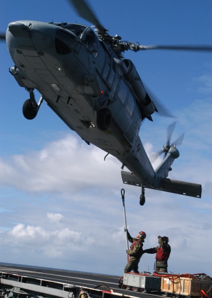 US Navy 040618-N-9742R-055 Aviation Ordnancemen uses a cargo pendant to attach a load of ordnance to a MH-60S Knighthawk 