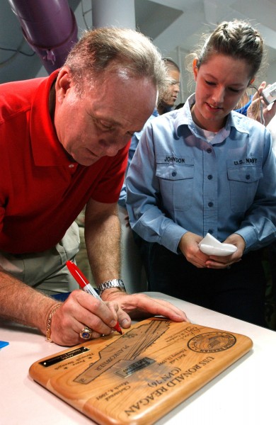 US Navy 040722-N-8148A-162 Michael Reagan, son of former President Ronald W. Reagan, autographs a plank owner plaque for Aviation Ordnanceman Airman Heather Johnson, of Saginaw, Mich