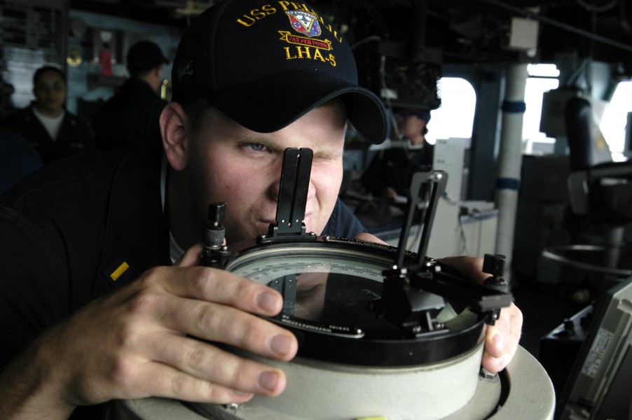US Navy 050624-N-1397H-054 Junior Officer of the Deck (JOOD), Ens. Daniel Sullivan uses the alidade on the bridge to take a bearing of a surface contact