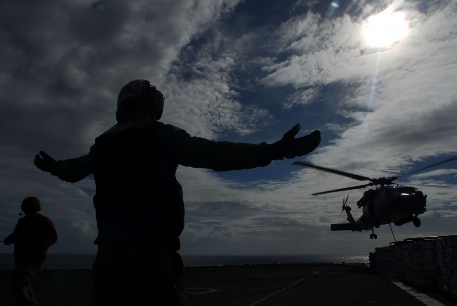 US Navy 070818-N-2659P-222 Aviation Ordnanceman 3rd Class Roger Sparks signals for a HH-60H Seahawk, with HS-8, to lift up from the loading area of the flight deck of USS John C. Stennis (CVN 74)