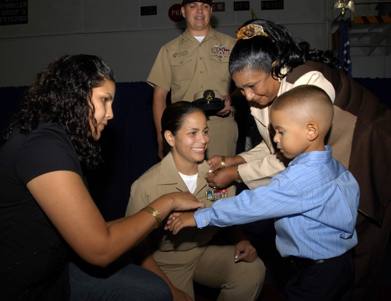 US Navy 070921-N-4133B-051 Family members of Chief Machinist's Mate Orlyn Fernandez pin anchors on her collar during a pinning ceremony held in the hangar bay aboard USS Ronald Reagan (CVN 76)