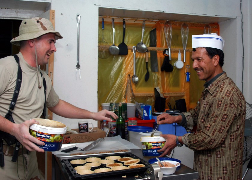 US Navy 071030-N-7415V-003 Culinary Specialist 2nd Timothy Wright, assigned to the Combined Security Transition Command-Afghanistan, teaches Nasim, the Afghan cook, how to make an apple dessert