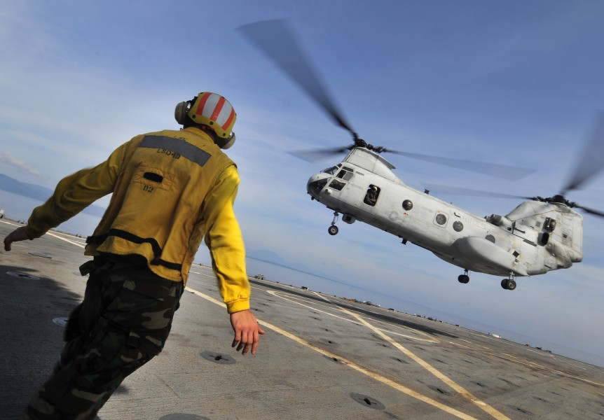 US Navy 091020-N-0807W-406 Aviation Boatswain's Mate (Handling) Airman Zachary D. Bruton signals to a Marine Corps CH-46 Sea Knight helicopter aboard the amphibious dock landing ship USS Harpers Ferry (LSD 49)