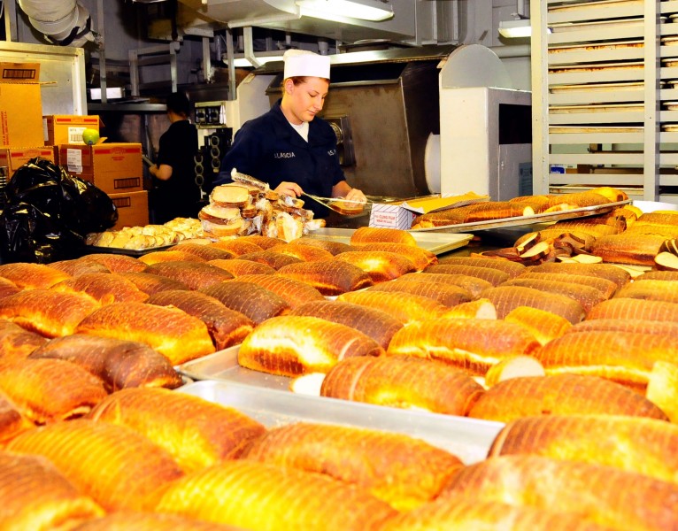 US Navy 100223-N-7939W-011 Aviation Ordnanceman Seaman Megan Alascia wraps fresh slices of baked bread