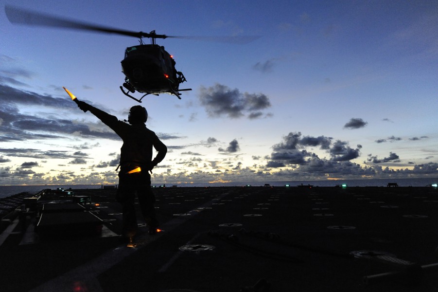 US Navy 100914-N-8335D-154 Boatswain's Mate 3rd Class Lanh Dinh directs a UH-IN Huey helicopter during take off from the amphibious dock landing sh