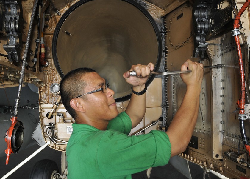 US Navy 100929-N-7103C-002 Aviation Structural Mechanic (Equipment) Airman Frederick Copuyoc removes bolts from the access panel of an F-A-18C Horn