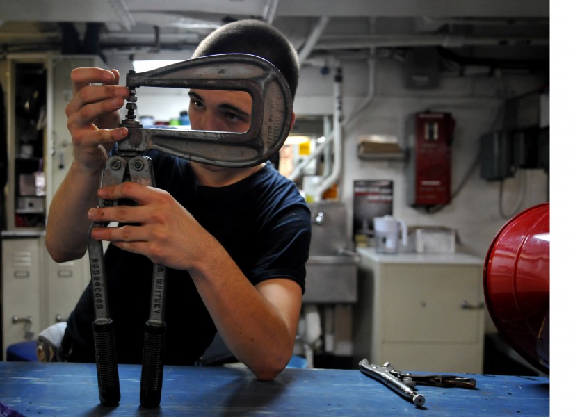 US Navy 120110-N-ZZ999-401 Airman Kaleb White adjusts a rivet squeezer while repairing a foreign object damage bucket