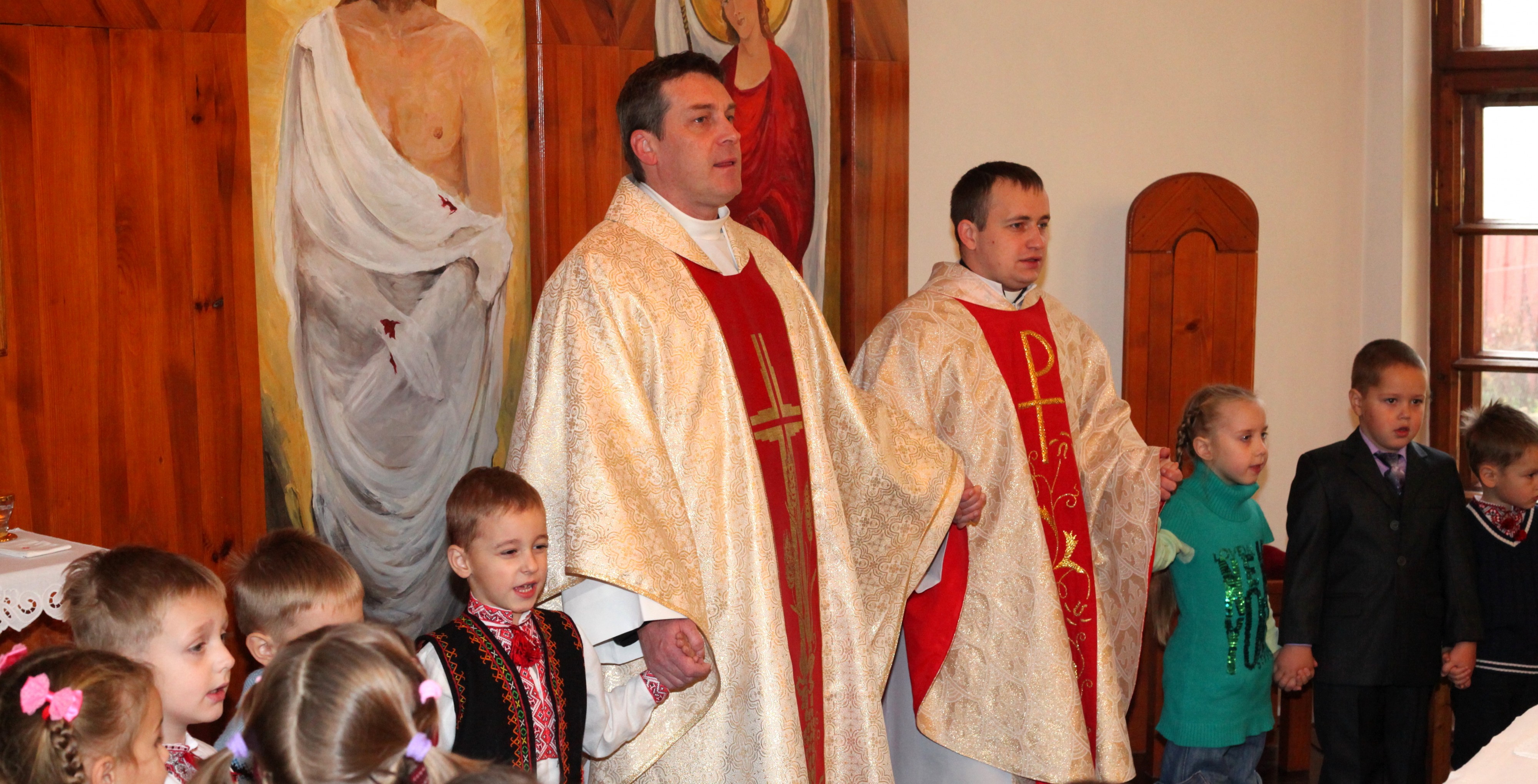 kids praying with priests at a Holy Mass in a Catholic Church