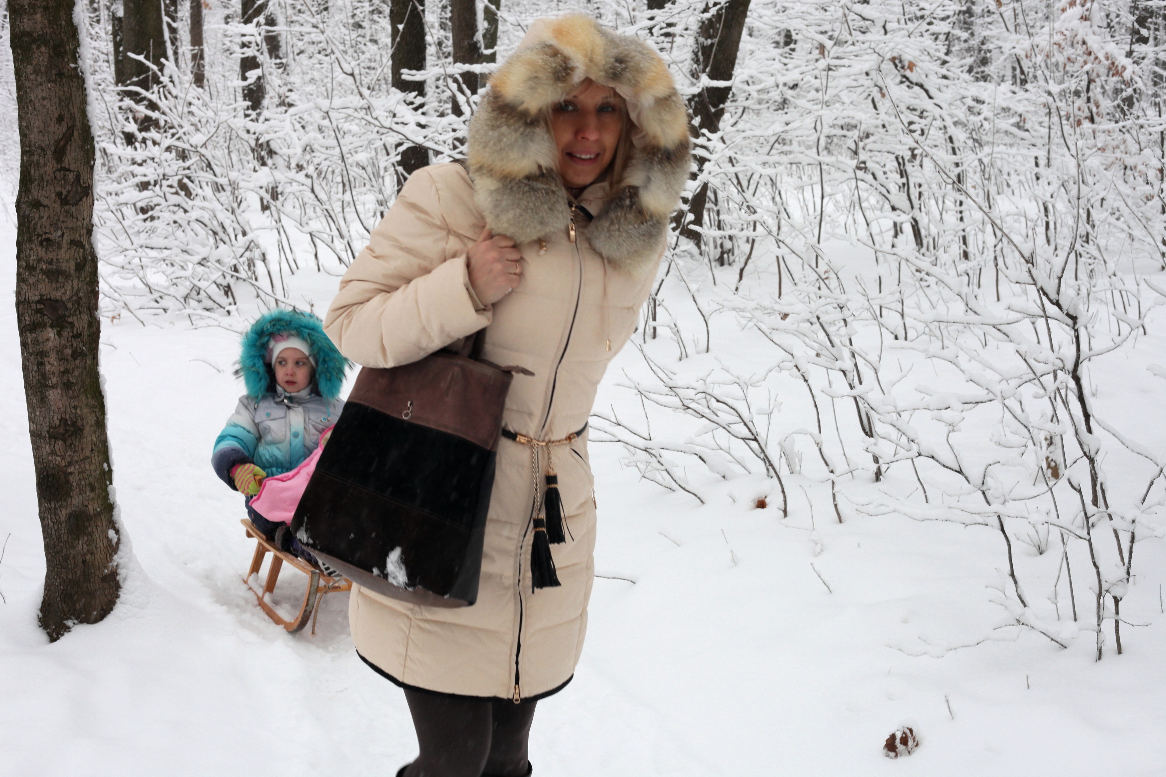 a young mother riding her daughter on a sled