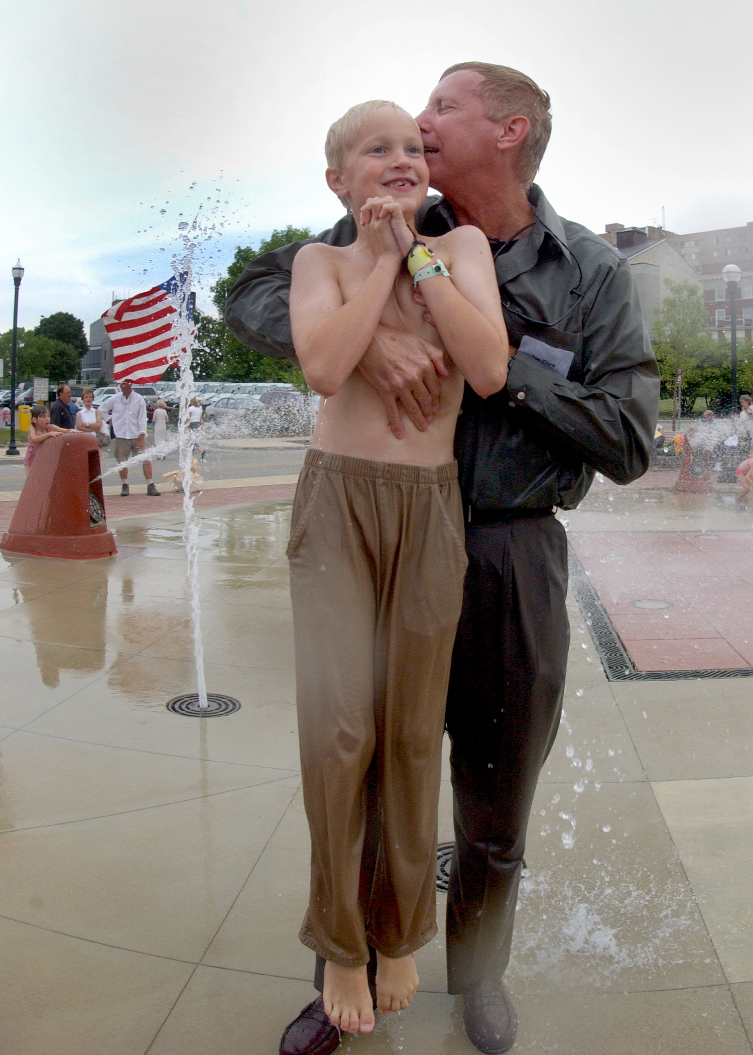 US Navy 030725-N-5576W-003 Dr. Jon Clark, husband of the late Astronaut, Capt. Laura Clark, hugs his son in the middle of the dancing waters fountain, downtown Racine, located on the shore of Lake Michigan
