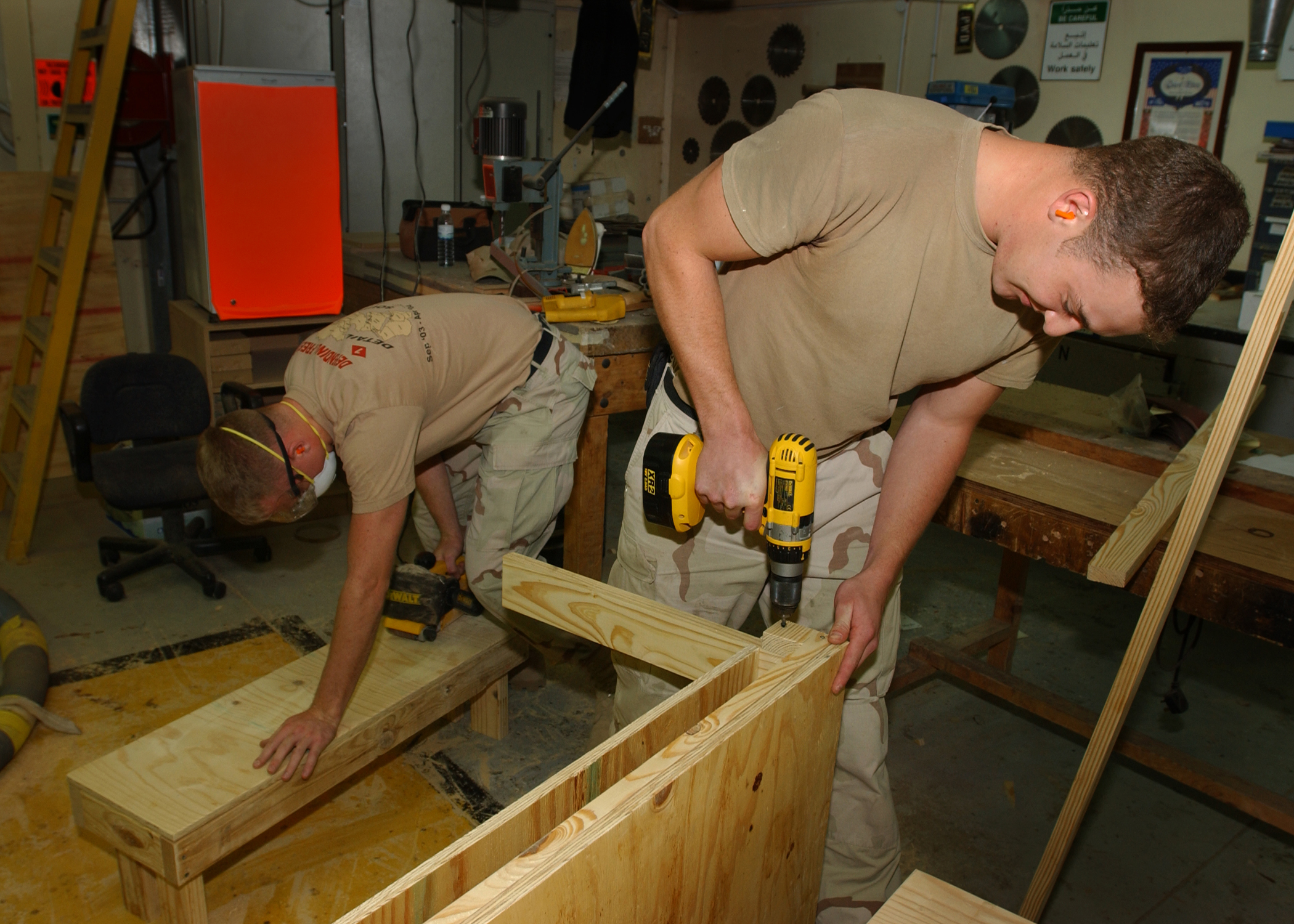 US Navy 040217-N-3994W-010 Builder 3rd Class Zack Mulally, right, builds a child^rsquo,s desk while Engineering Aide 2nd Class Mark Mulhern sands down a bench