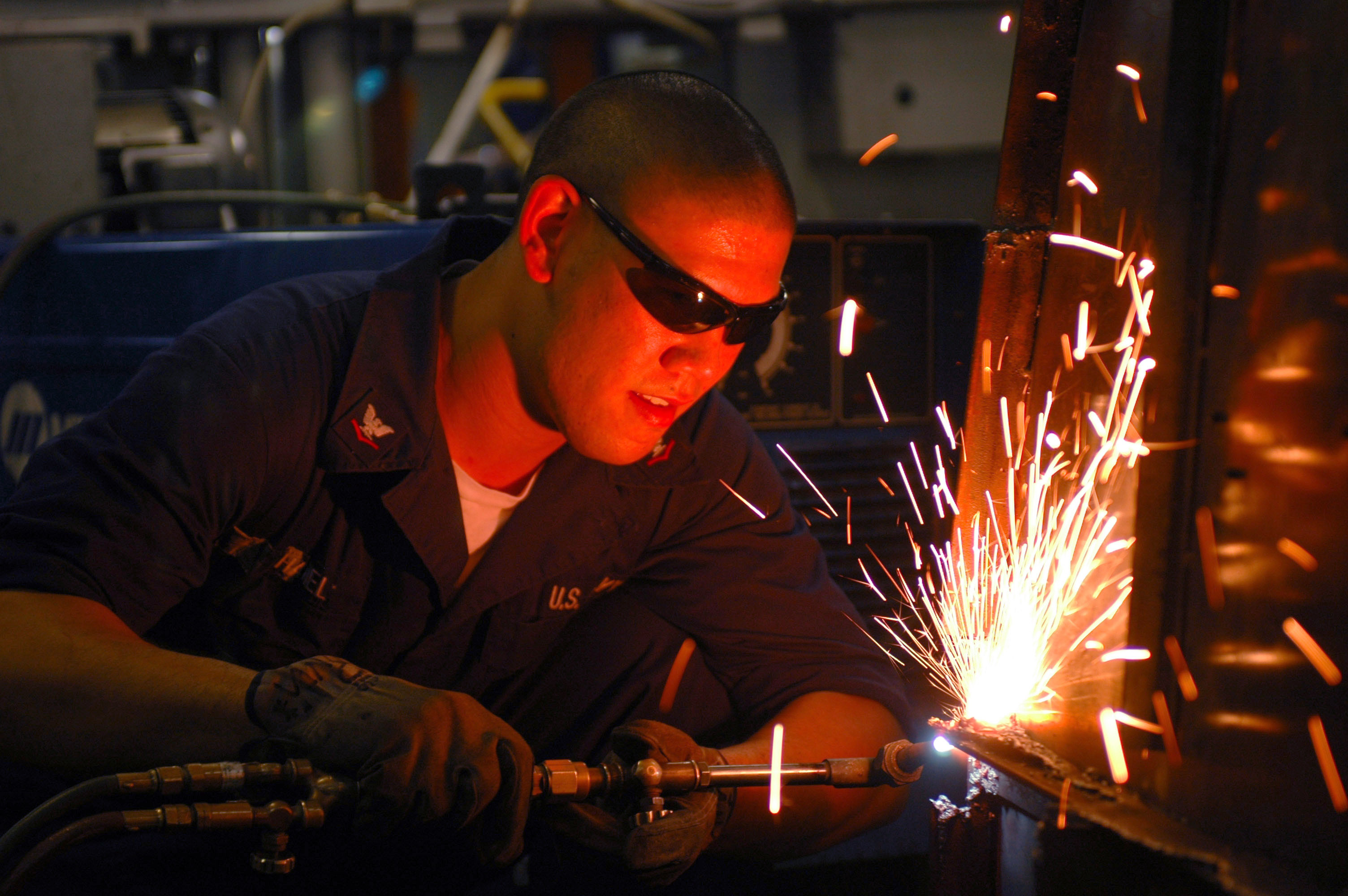 US Navy 061027-N-8119R-159 Hull Maintenance Technician 3rd Class Jeremy Hanel uses a cutting torch to cut apart old shelving aboard the nuclear-powered aircraft carrier USS Nimitz (CVN 68)