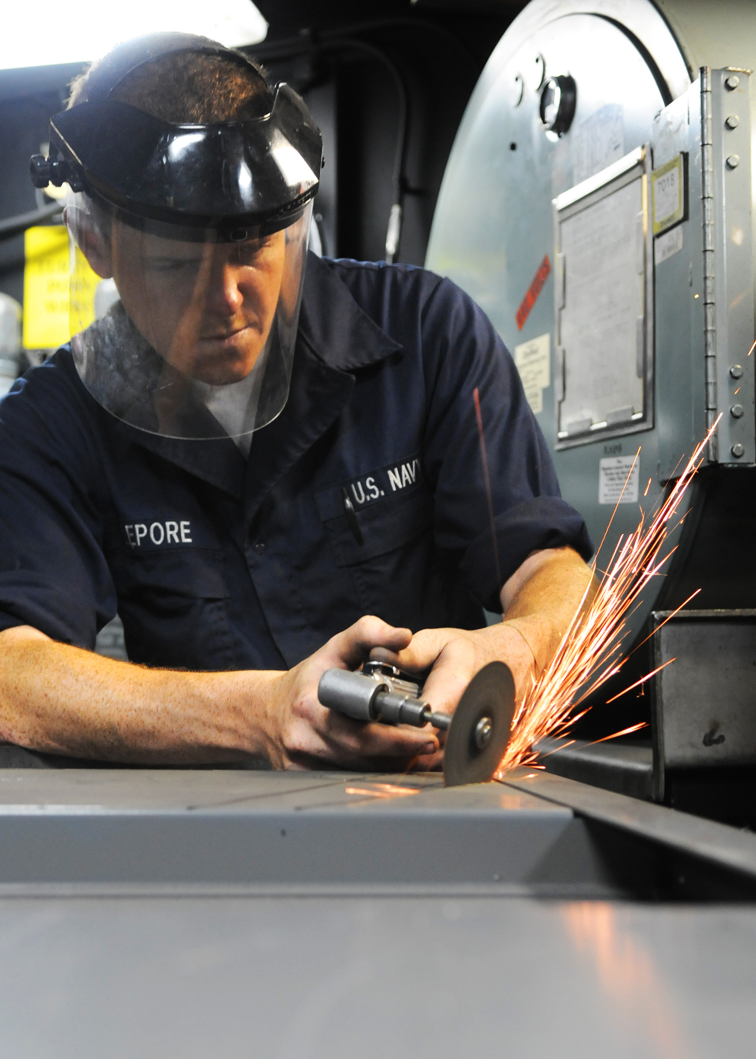 US Navy 101102-N-1004S-065 Machinery Repairman Fireman Mark Lepore, from Rochester, N.Y., uses a pneumatic die grinder to cut wiring holes in the b