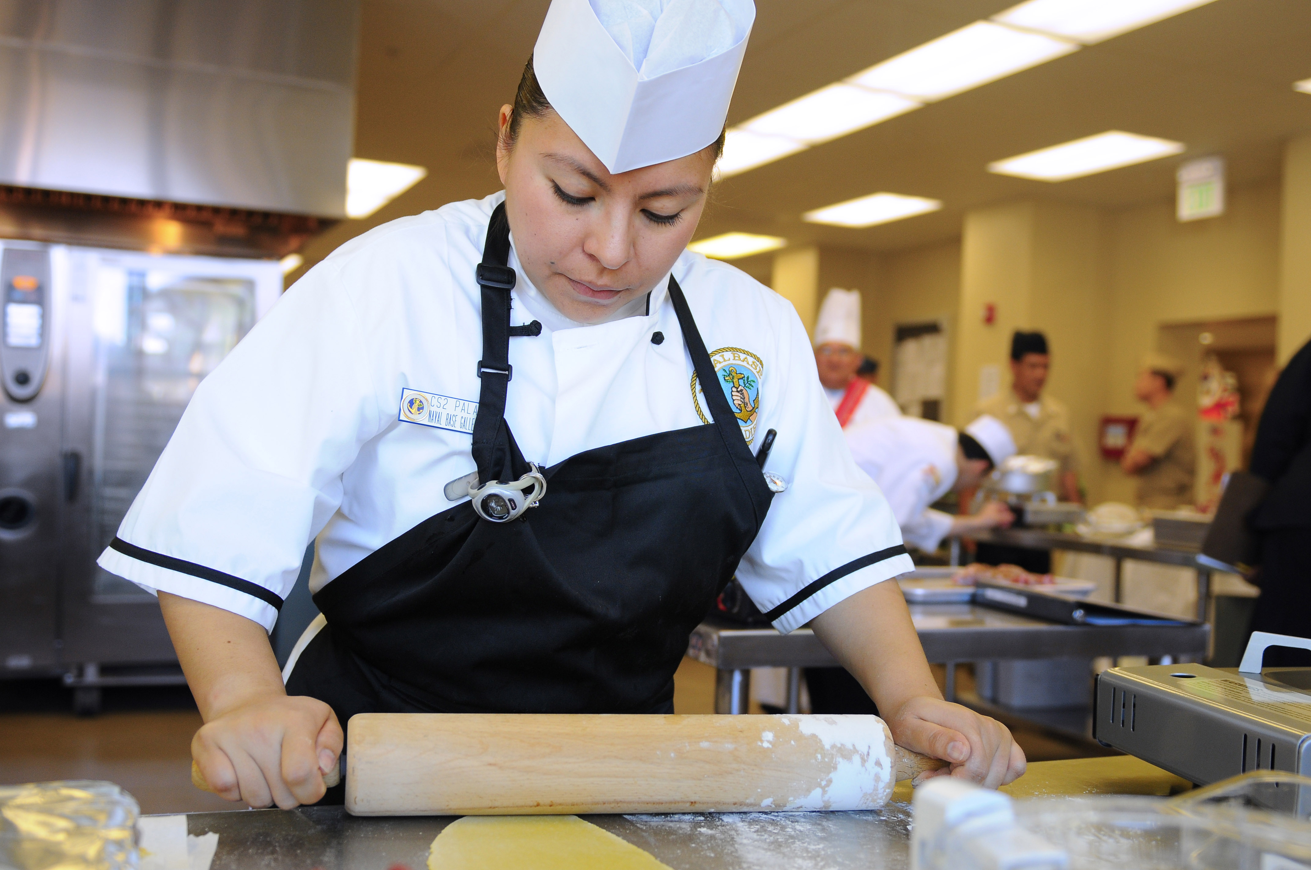US Navy 110301-N-1401J-017 ulinary Specialist 2nd Class Sophia Palafoxl rolls dough with a rolling pin during the 2011 Commander, Navy Region South