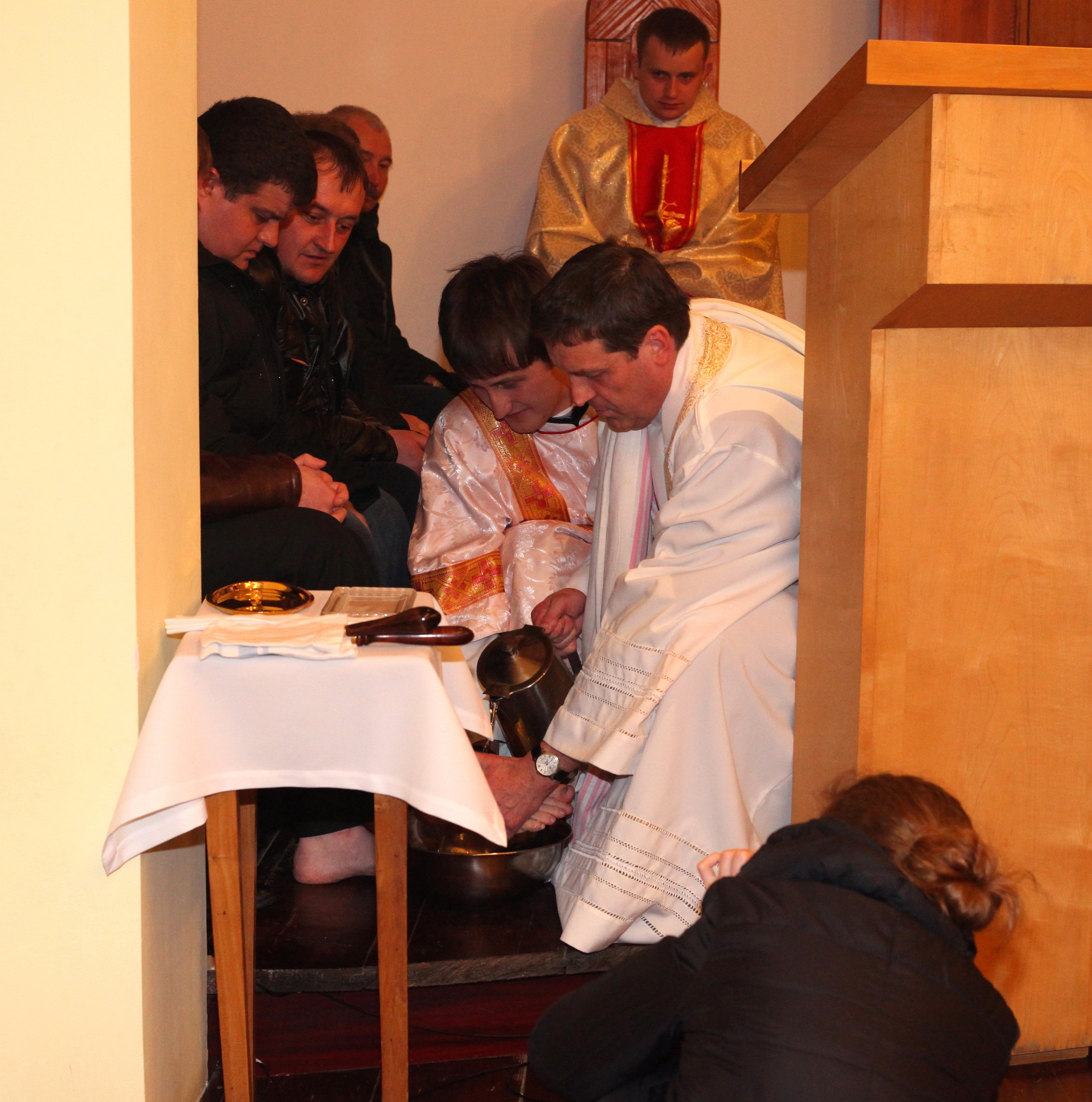 a Catholic priest washing feet of his parishiners