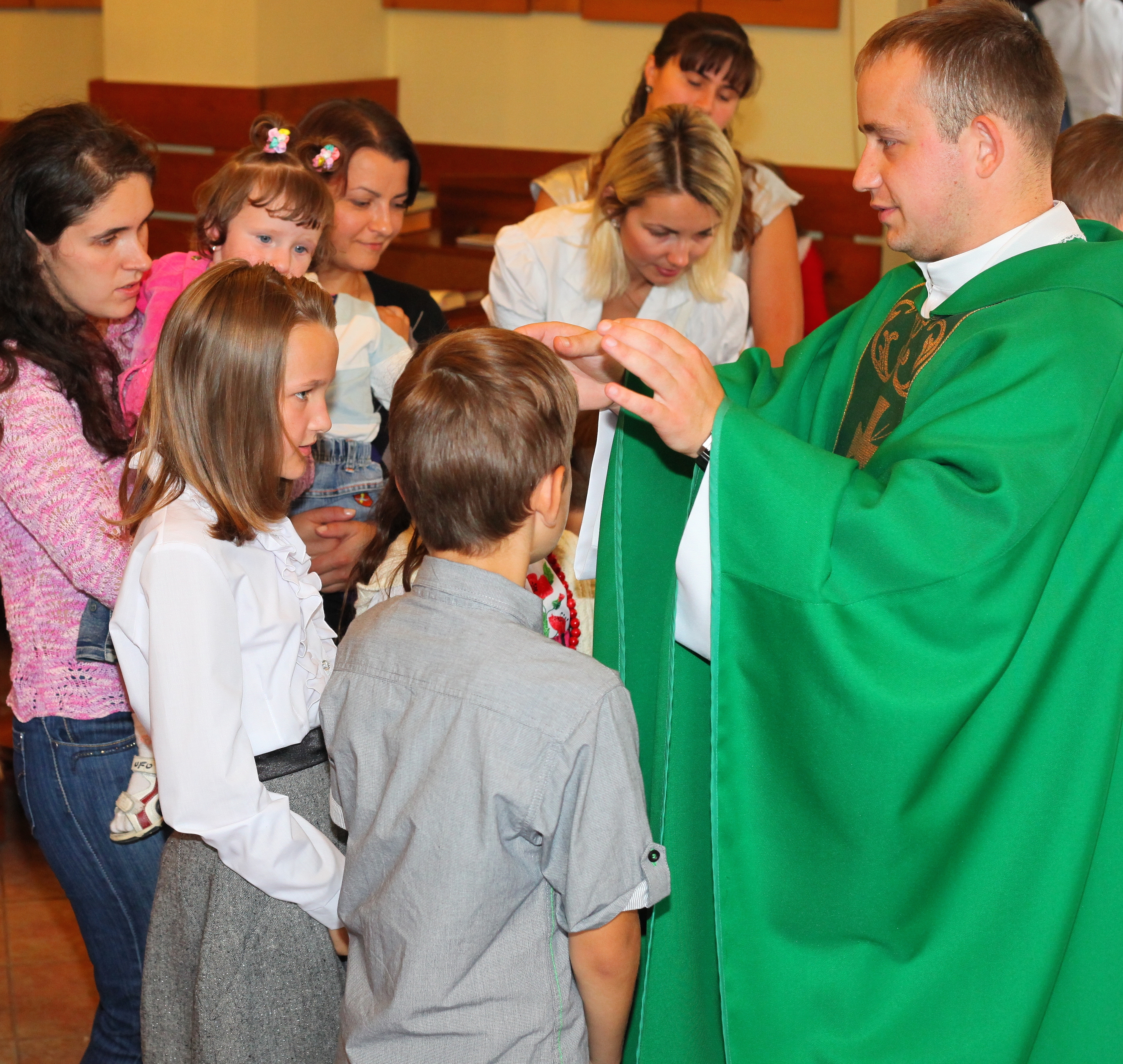 a young padre blesses children in a Church