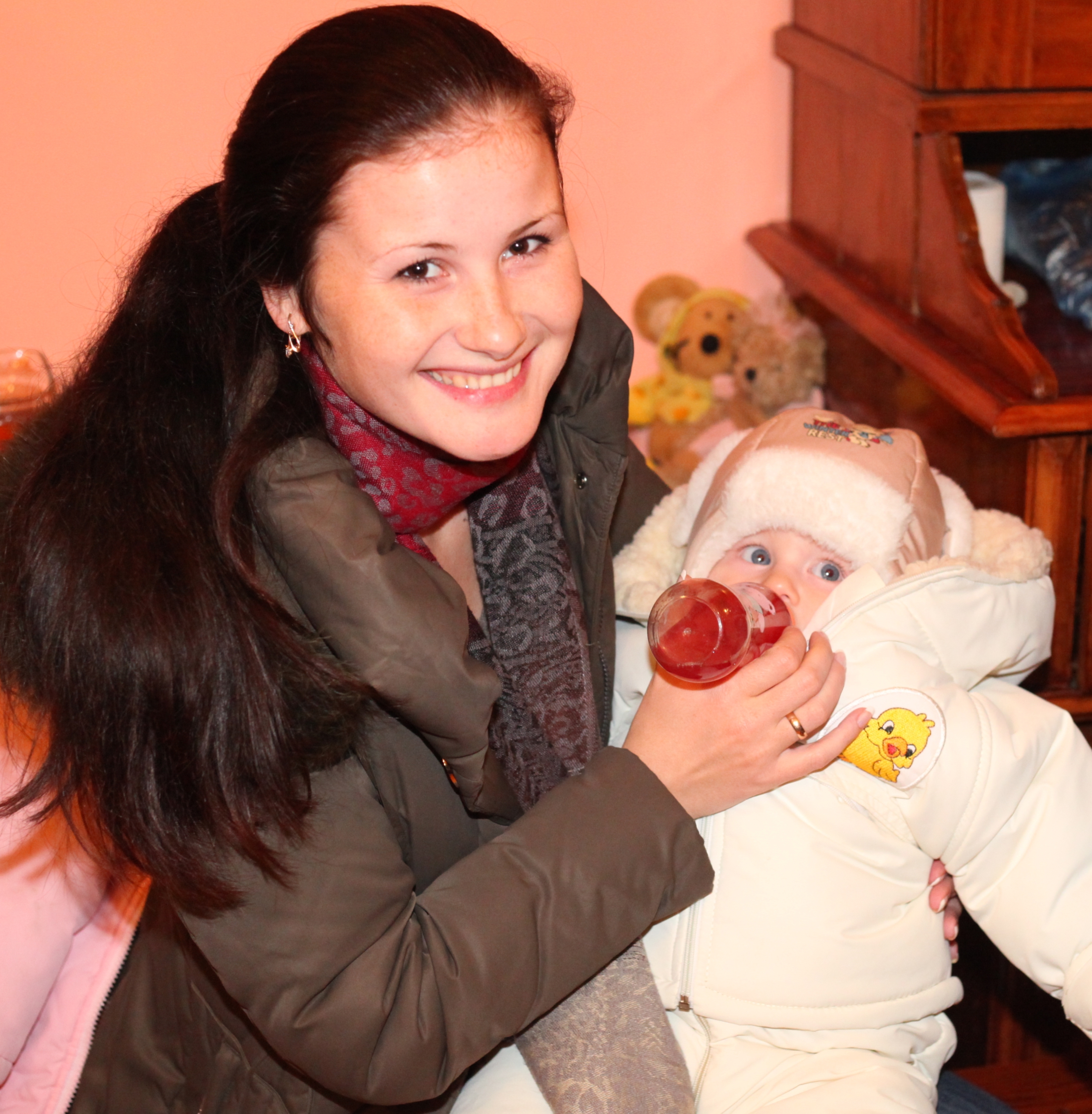 a beautiful smiling charming young brunette woman in a Church feeding a baby, photo 2