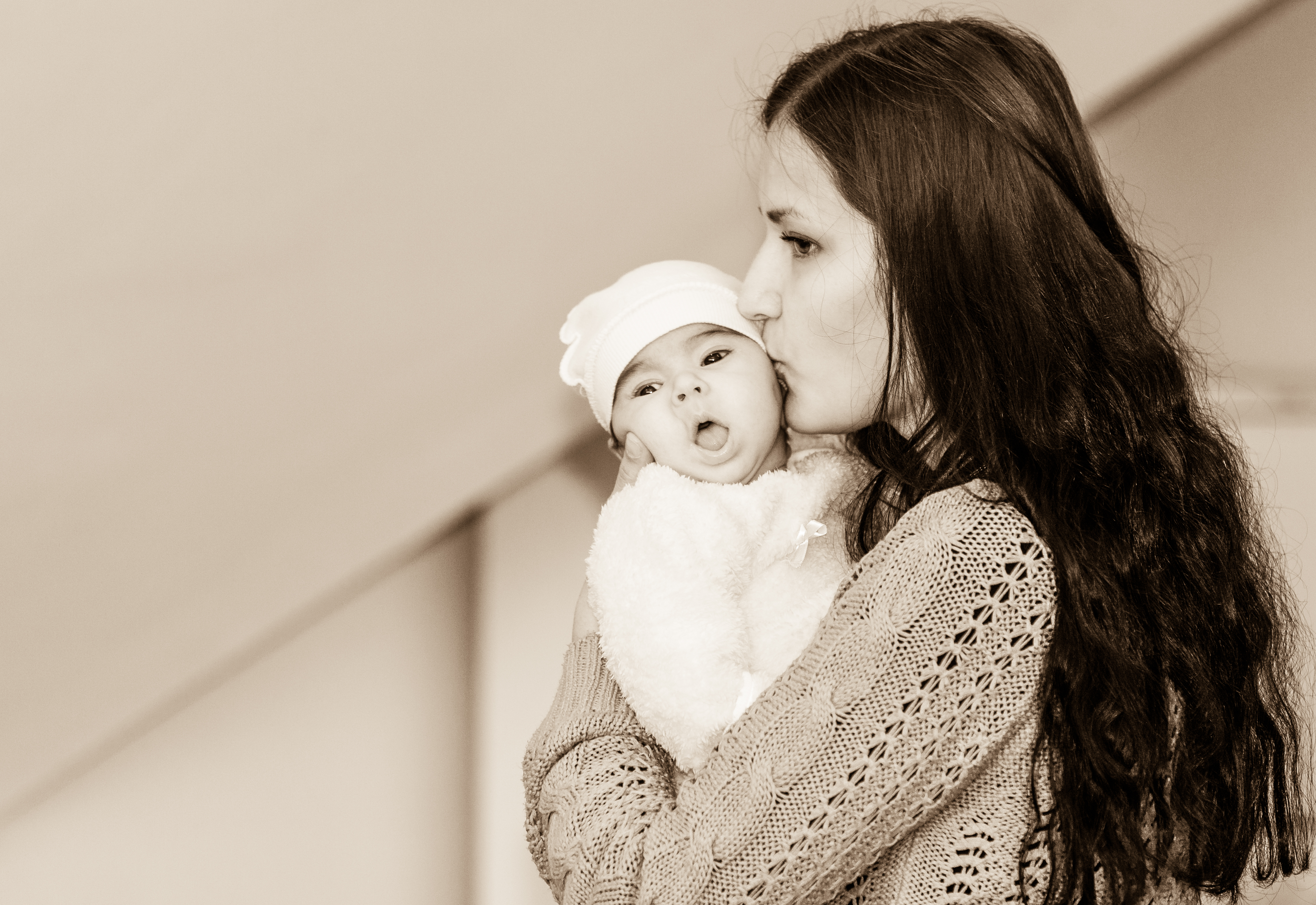 a beautiful young Catholic woman kissing her baby in November 2014, black and white
