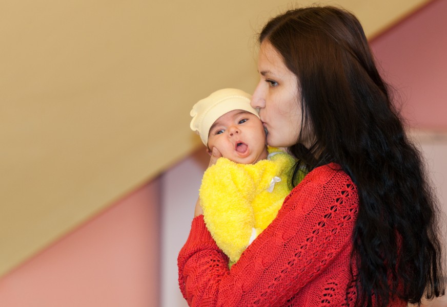 a beautiful young Catholic woman kissing her baby in November 2014