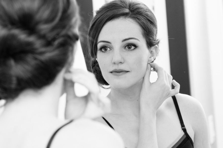Woman wearing earring in front of mirror