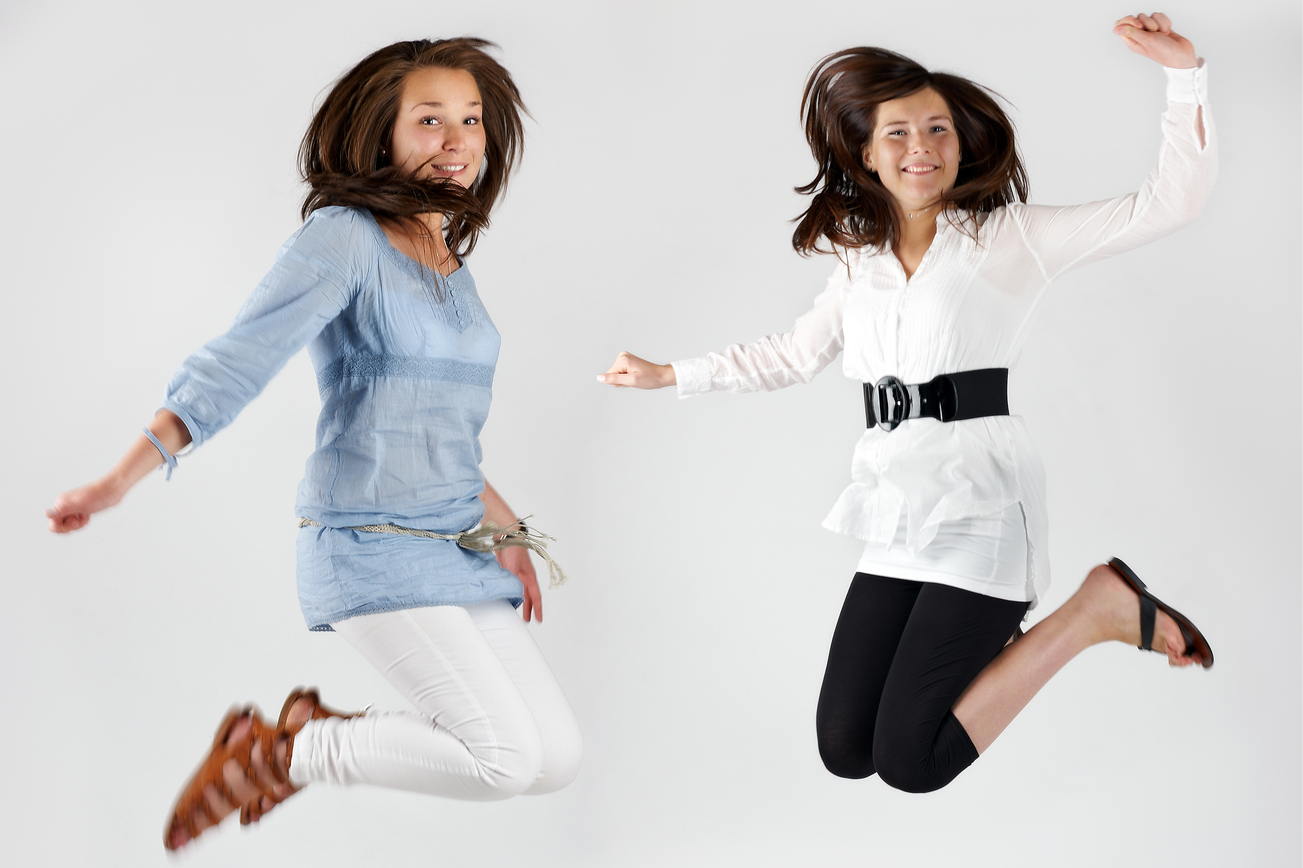 Woman in white Shirt and black pants and Woman in blue shirt and white pants jumping