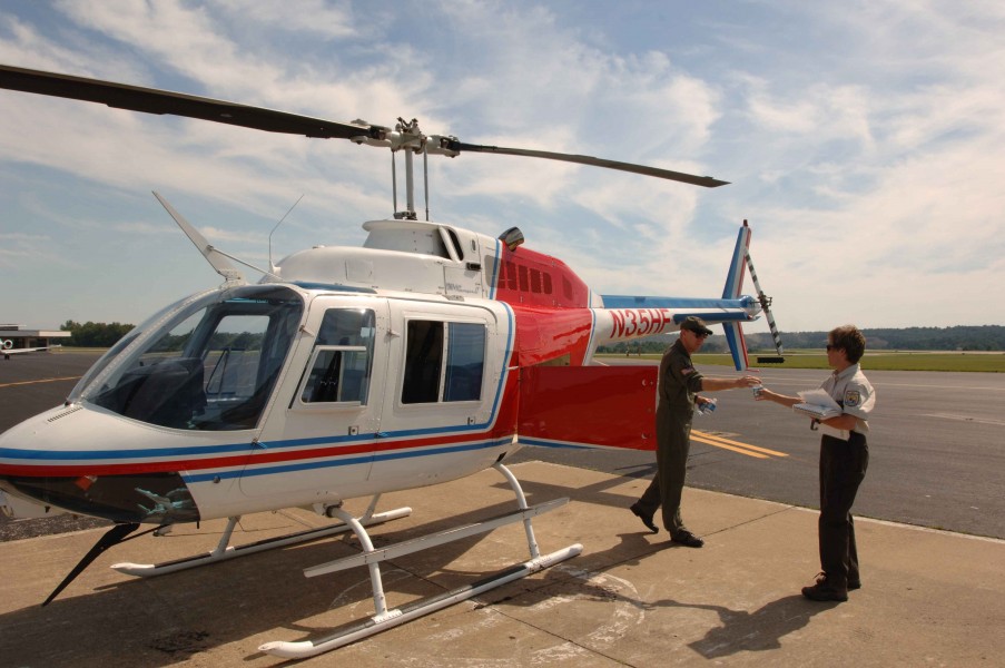 A helicopter pilot hands a employee a bottled water