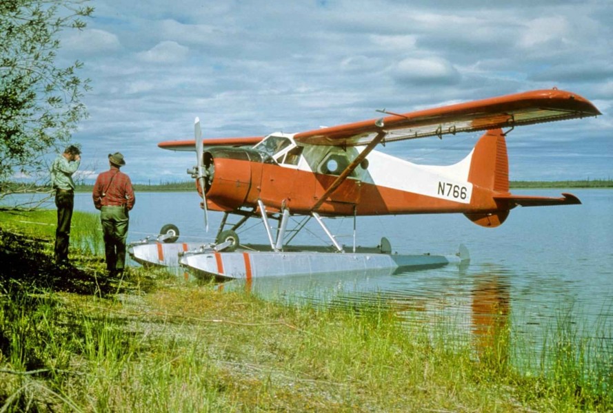 Float aircraft on shore with poeople beside